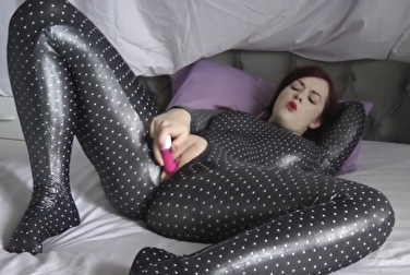 Брюнетка в латексном комбинезоне мастурбирует и играет с дилдо